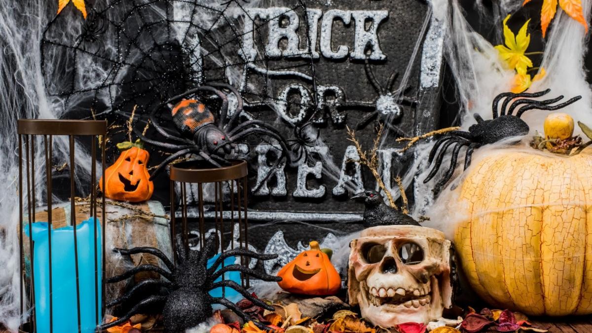 Halloween decor with pumpkins, skeletons, spiderwebs, and a sign that says "Trick or Treat". A plumbing nightmare is even scarier.